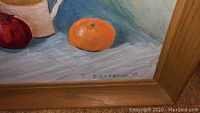 Close-up of framed still life painting with fruit on table, signature E. Lyzac ’87 visible
