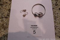 Photo of all four jewelry pieces arranged on white paper with lot number card.