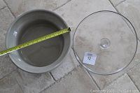 Stoneware dough maker pot with measuring tape showing diameter approx. 19 inches, alongside clear glass lid with knob handle.