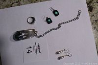 Photo of all five jewelry pieces - spoon pendant, cocktail ring, two pairs of drop earrings including green glass and engraved silver pairs.