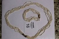 Full view of the multi-strand freshwater pearl necklace and matching bracelet laid out on a white background.