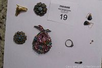 Full view of all jewelry items included in the lot laid out on a white surface with auction tag