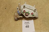 Underside view showing marks and detailed angel figure recognizable by blue draped cloth and gray hair