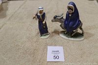 Full view of both figurines, Mary and baby Jesus on donkey, and Joseph standing holding a lantern and staff.