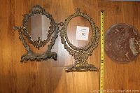 Both brass vanity mirrors side by side with one marble base visible and measuring tape for scale