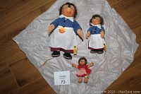Three German Steiff Micki dolls displayed on white tissue paper on wooden floor.