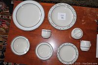Full set of dishes including plates, bowls, cups, creamer, sugar bowl, and serving pieces arranged on a table.