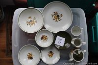 Full set showing plates, bowls, creamer, and mugs with floral decoration and a green rim