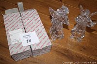 Two clear crystal angel figurines beside original Nachtmann box with printed paper, tied with a gray strap