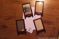 Four solid wood vintage picture frames arranged on wooden floor, one frame filled with old black and white photo, one glass broken