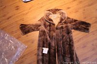 Full view of the coat laid flat showing its shape, medium size, short and wide sleeves, and button closure.