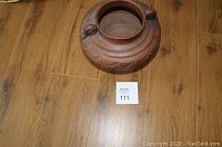 Top view of a large round stoneware pot with carved patterns and handle loops.