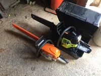 Two chainsaws on shed floor with carrying case open