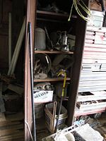 Shelf with long-handled tools and miscellaneous hardware boxes showing welding masks.