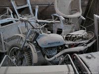 Overall side view showing dusty motorcycle among wicker chairs
