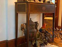 Wood hall table shown from an angle with visible front, side, and leg details. Items on top and underneath the table are visible.