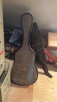 Two cases leaning against filing cabinet: one grey tweed hardshell and one black padded gig bag