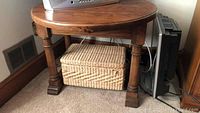Photo of the table showing the full round top and turned wood legs on carpeted floor next to a small woven basket.