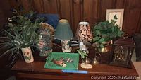 Full view of collection including lamps, faux plants, decorative tray, and other items arranged on wooden surface.
