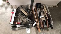 Collection of assorted kitchen utensils including knives, tongs, spoons, spatula, and other tools