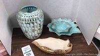 Photo showing large aqua teal ceramic vase, aqua teal leaf-shaped dish set, and 24kt gold painted leaf dish on wood table.