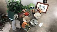 Overview of birdhouse collection, pottery bowls, plant, and framed art on floor