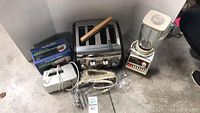 Sunbeam toaster, blender, mixer, electric knife, and chopper box together on gray surface