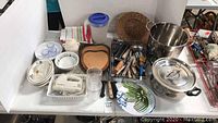 Overview of kitchen lot showing stock pots, cutting boards, utensils, dishes, mixer, and basket.