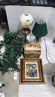Overview of antique globe lamp, green lamp, framed floral painting, decorative floral box and faux greenery