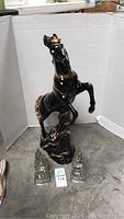 Photo showing front and side view of the black and gold ceramic horse statue with two glass bookends placed in front.