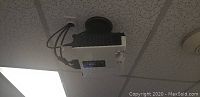 Sharp XR55X projector mounted on ceiling, front view showing lens and ventilation.