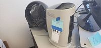 Honeywell Ionic Breeze air purifier and Honeywell small table fan placed side by side on a table, showing front and top parts.