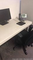 Desk with black chair, mouse pad, and office phone visible on the desk surface