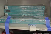 Five Logitech keyboard and mouse combo kits in original sealed turquoise packaging stacked on shelf, secured with blue tape