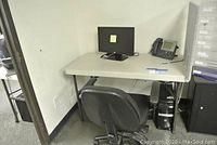 View of folding table with office chair, computer tower, desk phone, and privacy panel in corner of room.