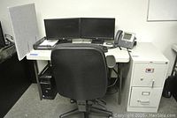 Full desk setup with chair, dual HP monitors, phone, computer tower, filing cabinet, and privacy panel visible. Phone, mouse, keyboard, and computer tower not included in lot.