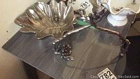 Pier 1 metal leaf bowl on a table alongside the metal and glass cheese board with floral arrangement nearby