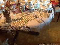 Complete set of cutlery laid out on a table showing forks, spoons, knives, glass cylinders and assorted pieces.