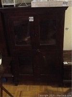 Front view of dark finish wood cabinet with four glass panel doors and metal knob handles.