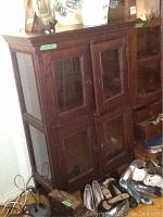 Full view of dark wood cabinet with glass panels and doors, surrounded by other items.