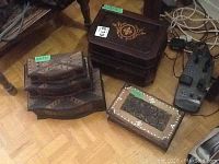 Photo showing five assorted wooden boxes with varied carving and inlay details on wooden floor.
