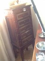 Full view of cabinet from front left showing five drawers and tapered legs