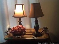 Full view showing the wooden tray with two table lamps and glass bowl with faux roses on top.