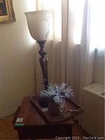 Wooden table lamp with frosted glass shade standing on a wooden tray with a winter decoration arrangement on the tray.