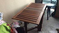 Wooden folding patio table showing the full length top surface with slats and some wear.