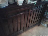 Front view of dark wood sideboard showing sliding wood-slat framed glass doors