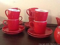 Photo of eight stacked red cups on matching saucers, glossy finish