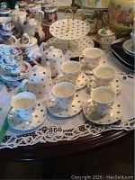 Goldie by Robert Gordon tea set: six teacups and saucers, two teapots, two-tiered dessert server on lace cloth on table
