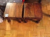 Photo showing top view of two matching wooden stools side by side on wooden floor.