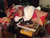 Photo showing carved wood tray holding boucle throws and geometric decorative pillows in red and beige colors.